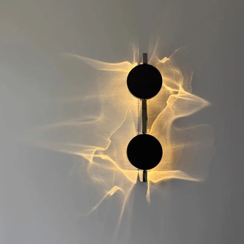 Duo wall sconce with warm ripple light across a gray wall, two discs on a vertical bar — Casa Norex