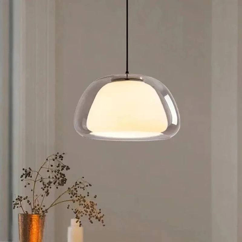 Double glass dome pendant light glowing beside a vase of dried branches — Casa Norex