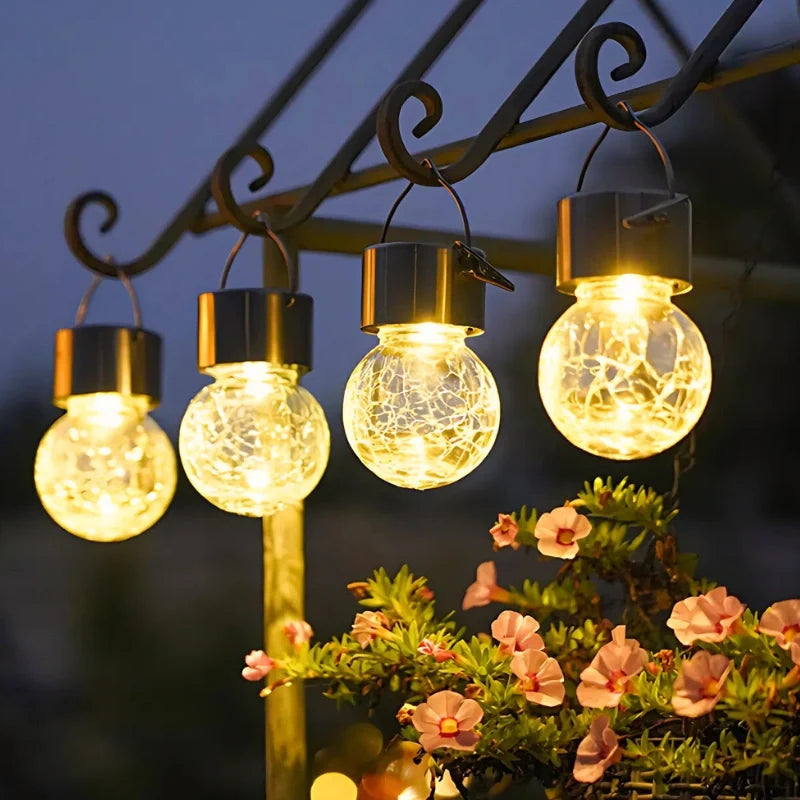 Four solar lanterns hanging in a row from a metal bracket — Casa Norex