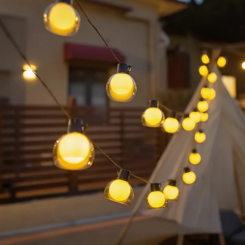Solar globe string lights hung beside a house and awning — Casa Norex