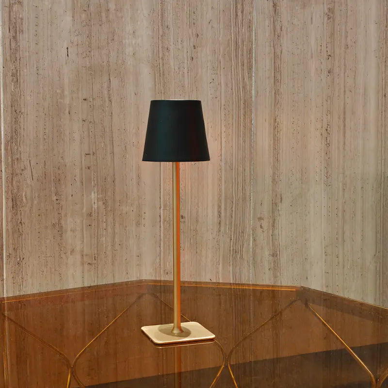 Black and gold table lamp on a wood table — black shade with gold base — Casa Norex