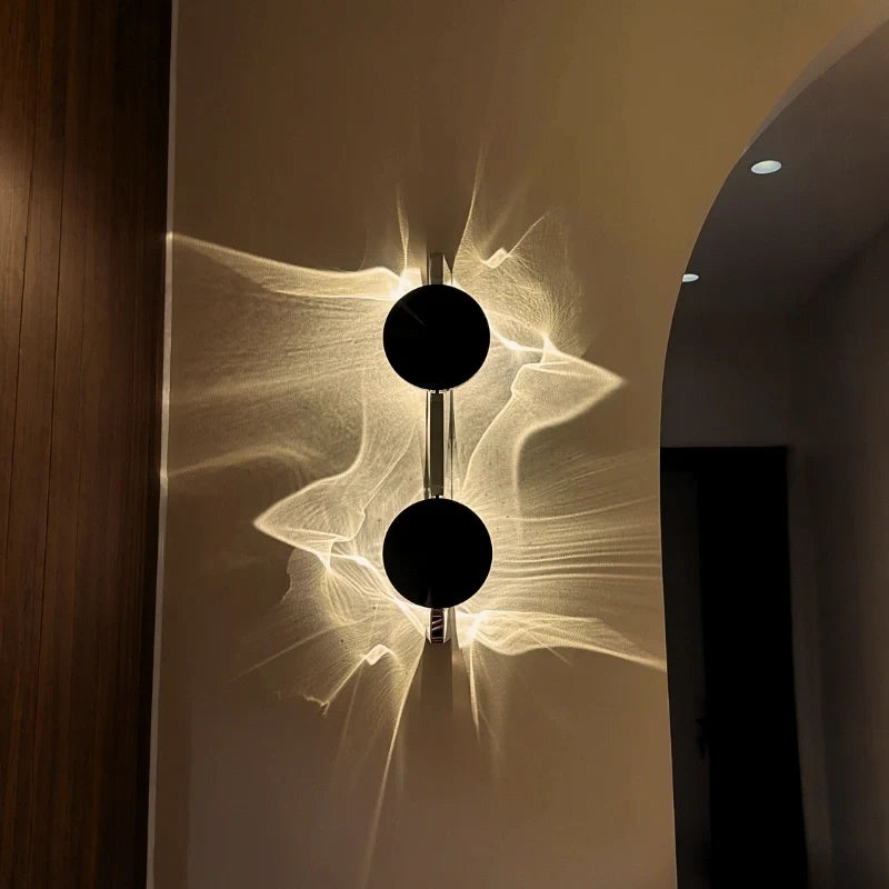Duo wall sconce in interior setting beside a wood panel and arched doorway — two stacked discs | Casa Norex