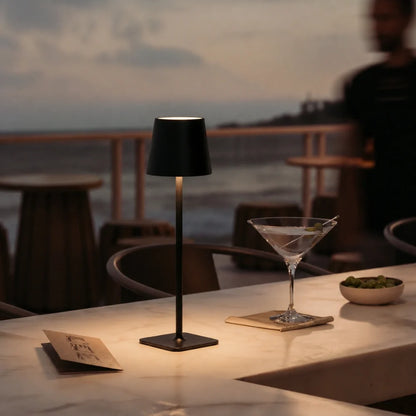 Cordless table lamp — matte black iron body with touch dimming on an outdoor dining table | Casa Norex