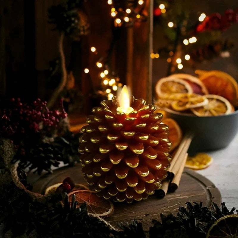 Flameless candles — golden brown pinecone with flickering LED flame beside dried orange slices | Casa Norex