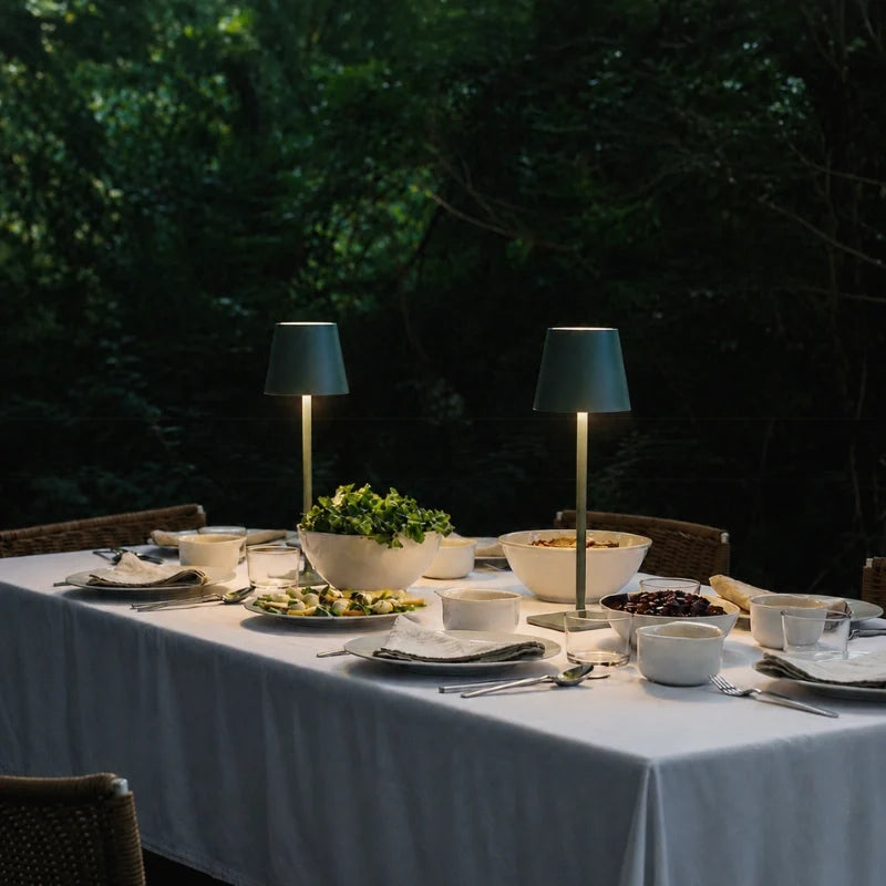 Two lamps lit on an outdoor dinner table set for a meal — Casa Norex