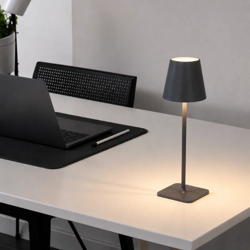 Dark grey table lamp on a white work desk beside a laptop — Casa Norex
