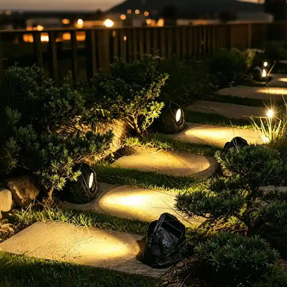 Stone-look solar lights lighting a garden path and shrubs at night