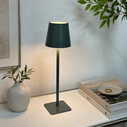Dark green-grey table lamp on a desk with books and a vase — Casa Norex