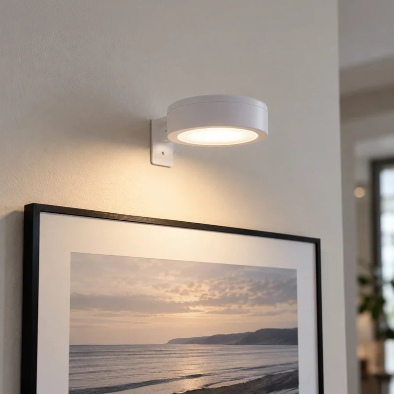 Cordless rechargeable picture light close-up above a framed seascape