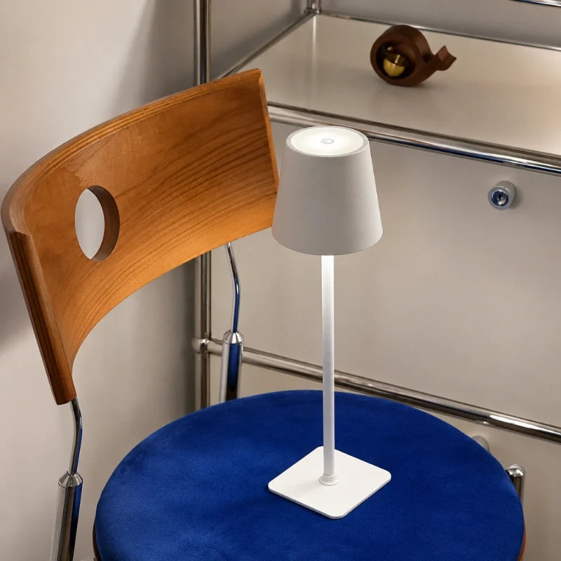 White table lamp on a chair-side surface beside a blue stool — Casa Norex