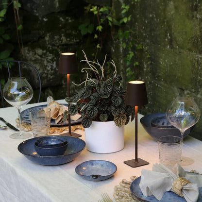 Small table lamp glowing among blue dishes and glasses at a table — Casa Norex