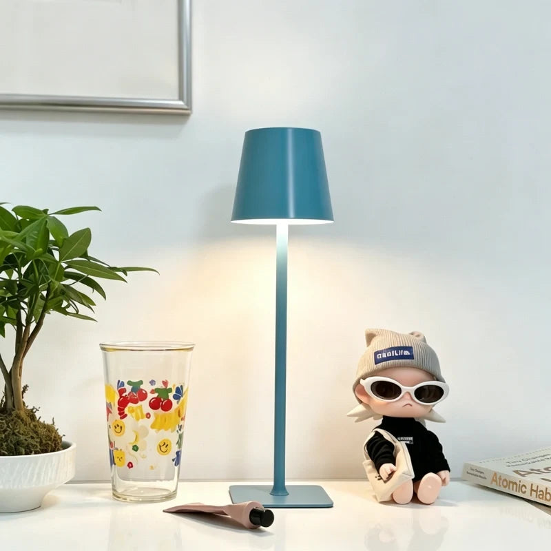 Matte blue table lamp on a white table beside glassware — Casa Norex