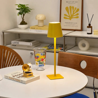 Matte yellow table lamp on a round table with books and a plant — Casa Norex