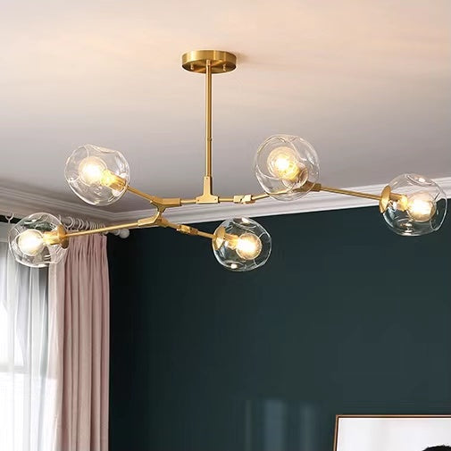 Close-up of staggered brass arms on clear globe chandelier | Casa Norex