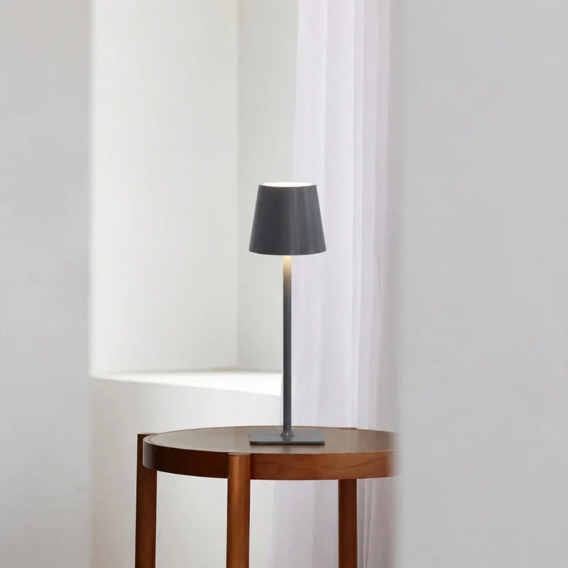 Matte grey table lamp on a round wood side table by a window — Casa Norex