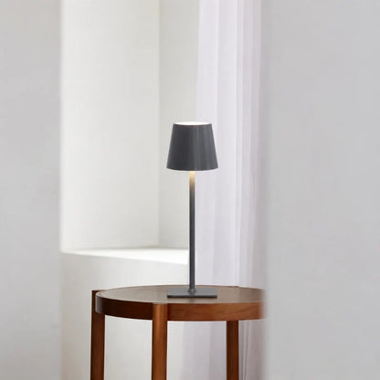 Matte grey table lamp on a round wood side table by a window — Casa Norex