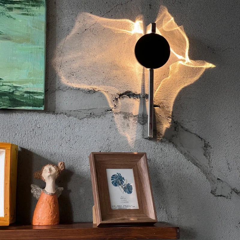 Solo wall sconce on a textured concrete wall above a shelf with framed art — Casa Norex