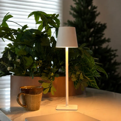 White table lamp on a dining table beside a mug and a plant — Casa Norex