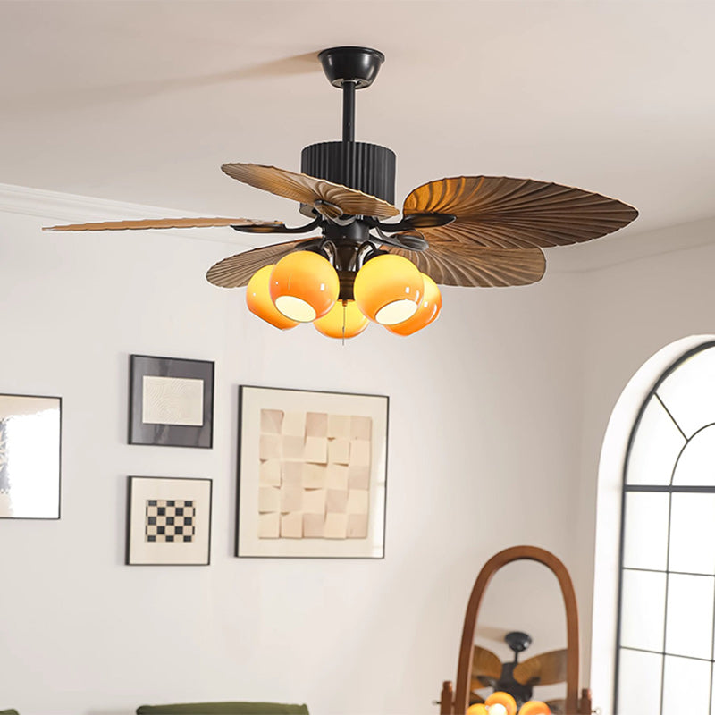 Close-up of round glass lampshade and banana-leaf blade on ceiling fan light | Casa Norex