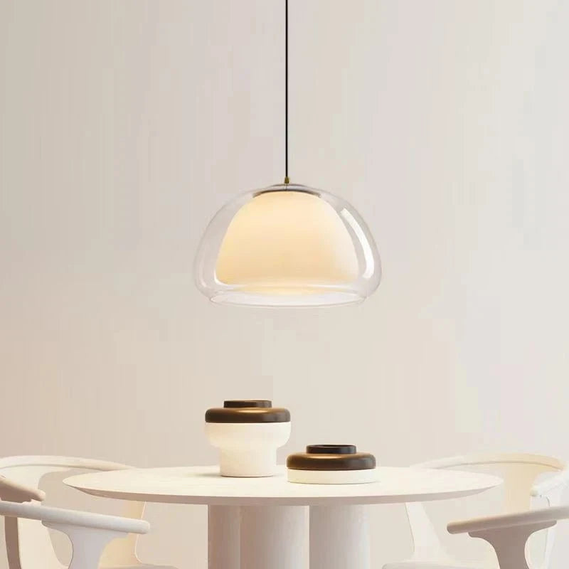 Double glass pendant light over a round white table with ceramic bowls — Casa Norex
