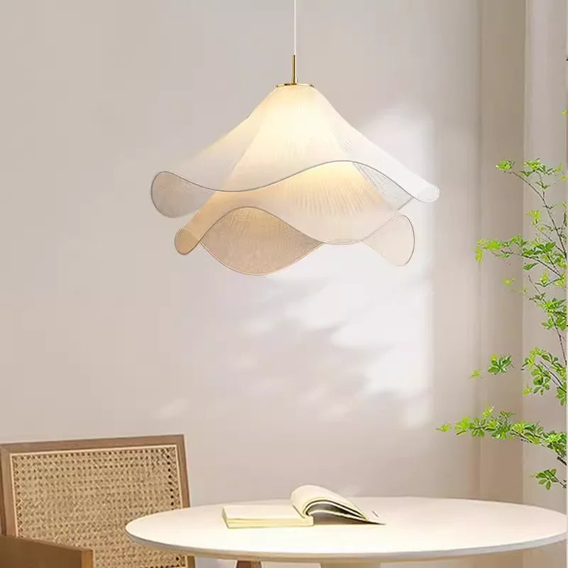 Fabric flower pendant light over a round table with a rattan chair and open book | Casa Norex
