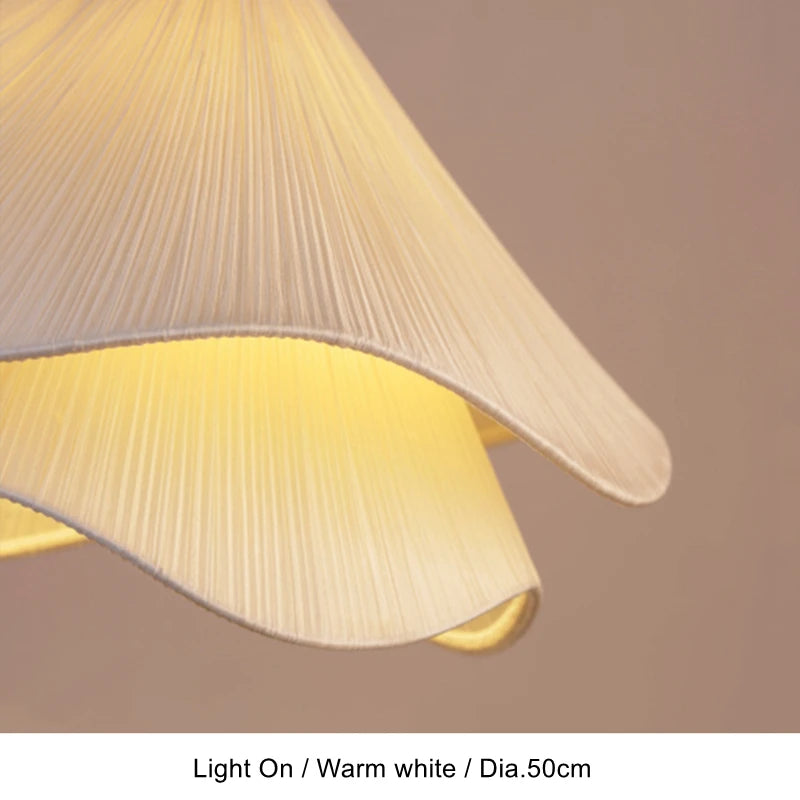Close-up of lit pleated fabric shade on a flower pendant light in warm white — Casa Norex