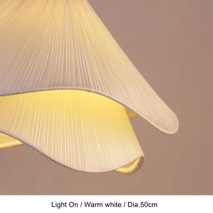 Close-up of lit pleated fabric shade on a flower pendant light in warm white — Casa Norex