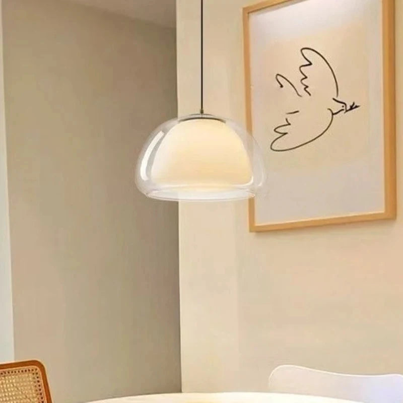 Dome glass pendant light beside framed bird line art above a dining table — Casa Norex