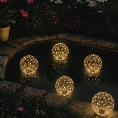 Warm white floating solar light orbs on the water beside the pool edge