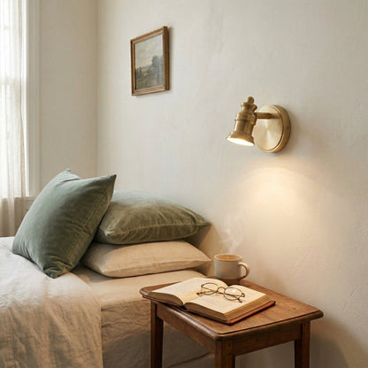 Single-head brass wall sconce beside a bed with a framed picture above — Casa Norex