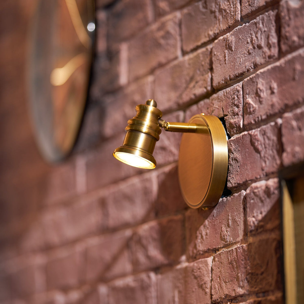 Brass spotlight head wall sconce close-up on a red brick wall — Casa Norex