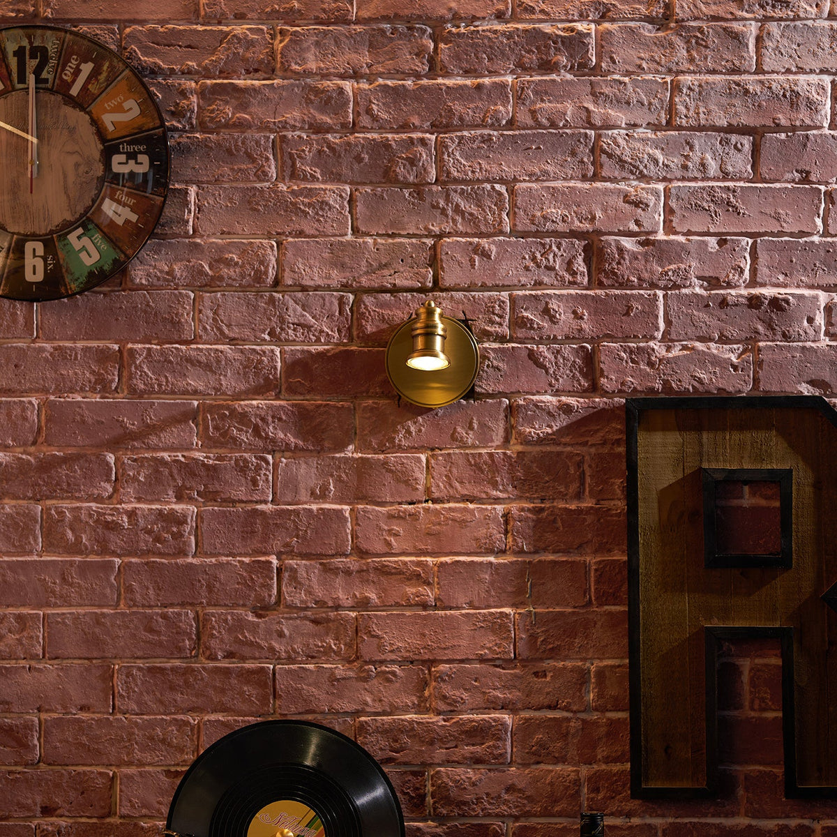Single-head brass wall sconce on brick beside a vintage radio — Casa Norex