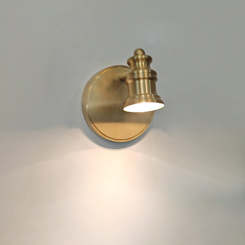 Single-head brass wall sconce with a soft glow on a grey wall — Casa Norex
