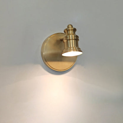 Single-head brass wall sconce with a soft glow on a grey wall — Casa Norex