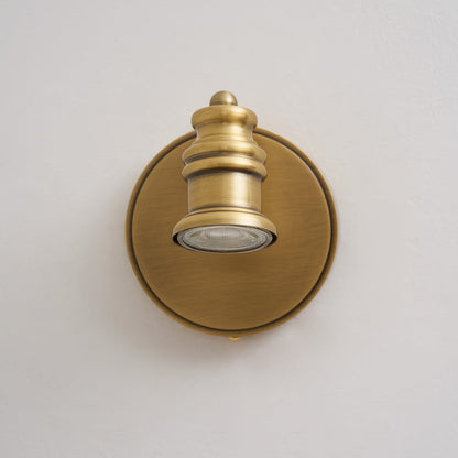 Front view of a single brass spotlight head on a round backplate — Casa Norex