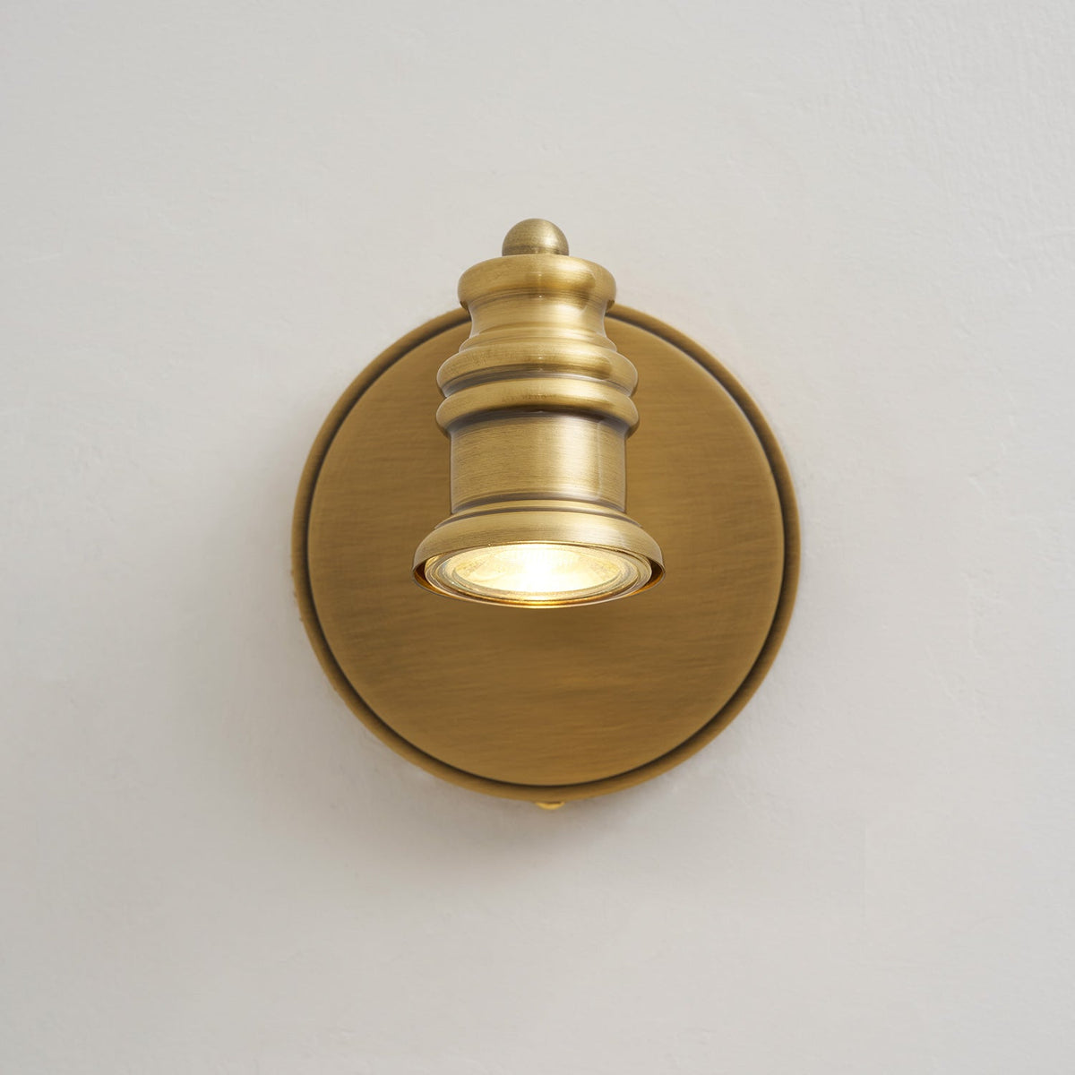 Single brass spotlight head wall sconce, front view on a light wall — Casa Norex