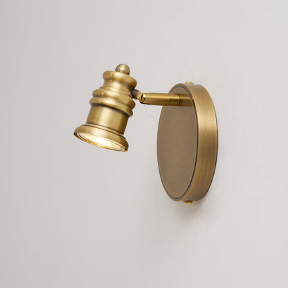 Side view of a single brass spotlight head on a round backplate — Casa Norex