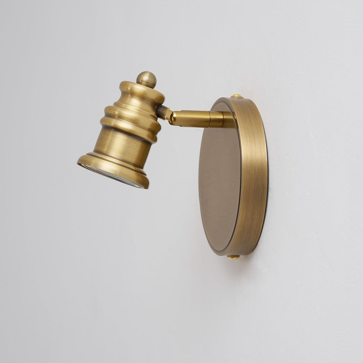Angled view of a single brass spotlight head on a round backplate — Casa Norex