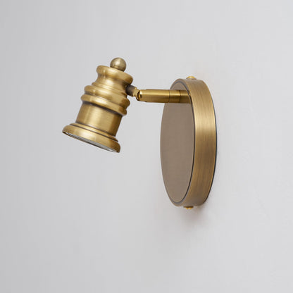 Angled view of a single brass spotlight head on a round backplate — Casa Norex