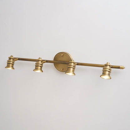 Three-head brass spotlight bar on a white wall, front view — Casa Norex
