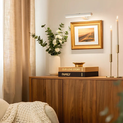 White cordless picture light above a framed painting beside candlesticks | Casa Norex