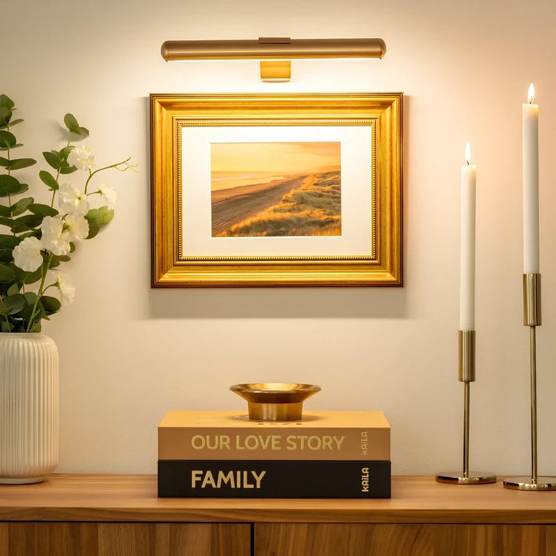 Gold picture light above a framed print and gold candlesticks — Casa Norex