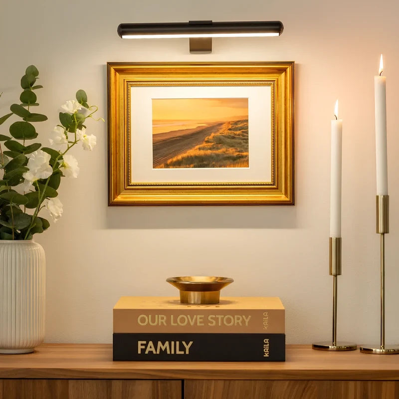 Black picture light above a framed print and gold candlesticks — Casa Norex
