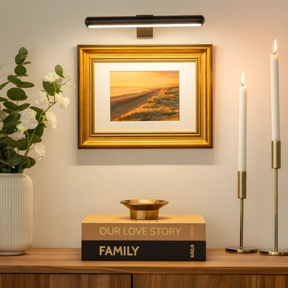 Black picture light above a framed print and gold candlesticks — Casa Norex