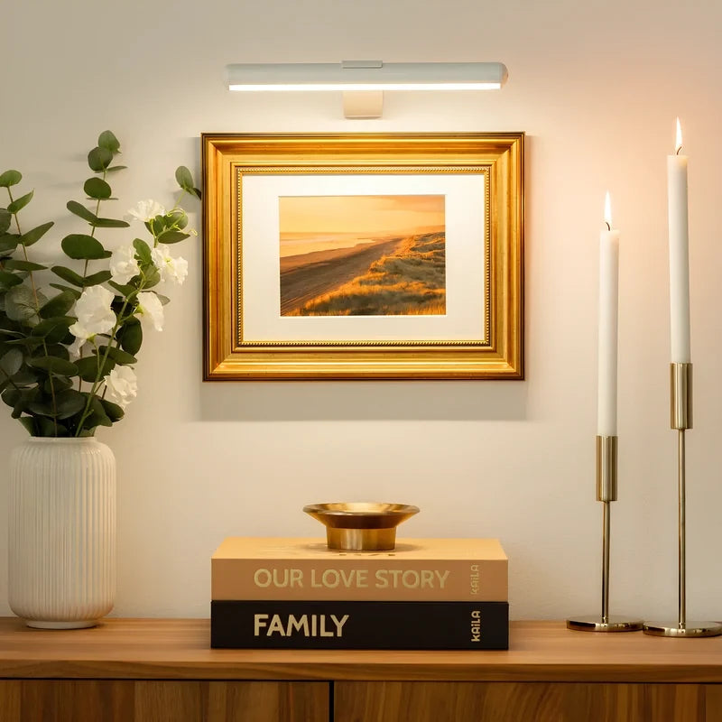 White picture light above a framed print and gold candlesticks — Casa Norex