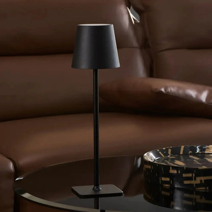 Matte black table lamp in front of a brown leather sofa — Casa Norex