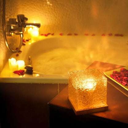 Borealis acrylic northern lights cube lamp glowing amber on a wood base beside a bathtub | Casa Norex