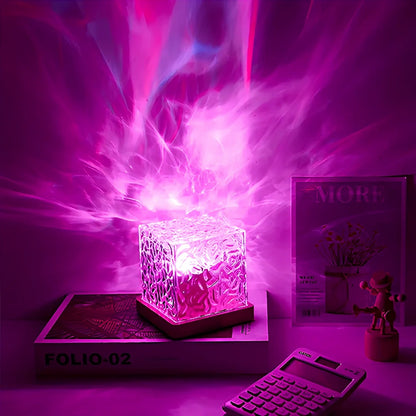Magenta glowing acrylic cube lamp on a stack of books with vivid purple light behind — Casa Norex