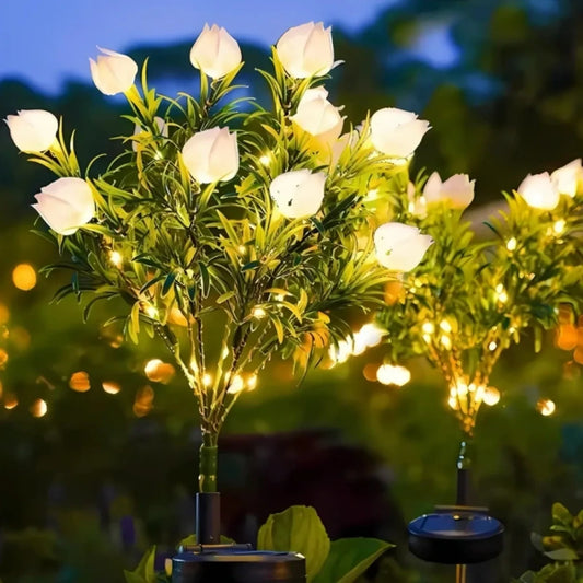 White solar flower lights glowing on tall stems in a garden at dusk | Casa Norex