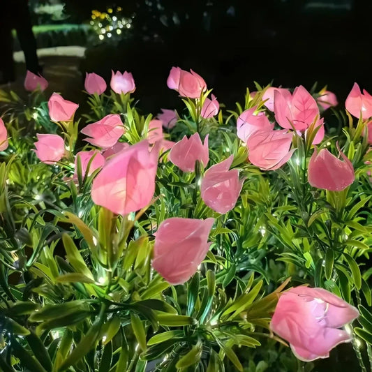 Pink faux rose stake lights with a soft warm glow in a flower bed | Casa Norex
